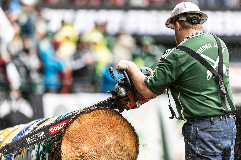 Timbers Army fan cutting a log with a chainsaw